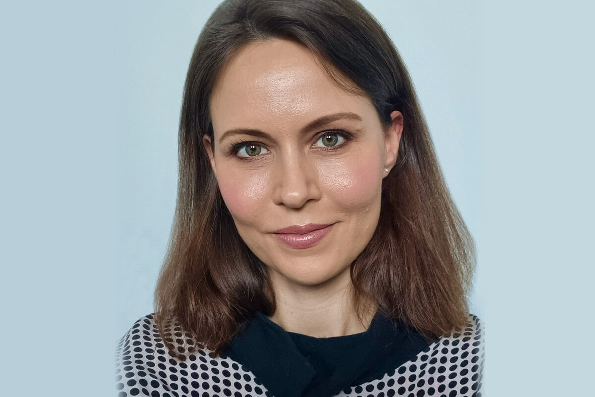 Portrait image of Jess Cantlon. She has shoulder-length brown hair, green eyes and is wearing a spotty navy blue and white sweater.