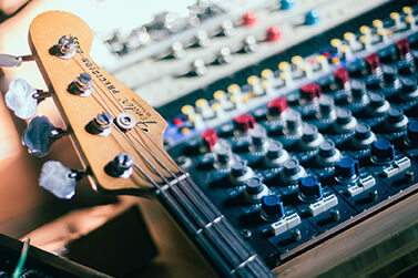 A bass guitar leaning against a mixing desk