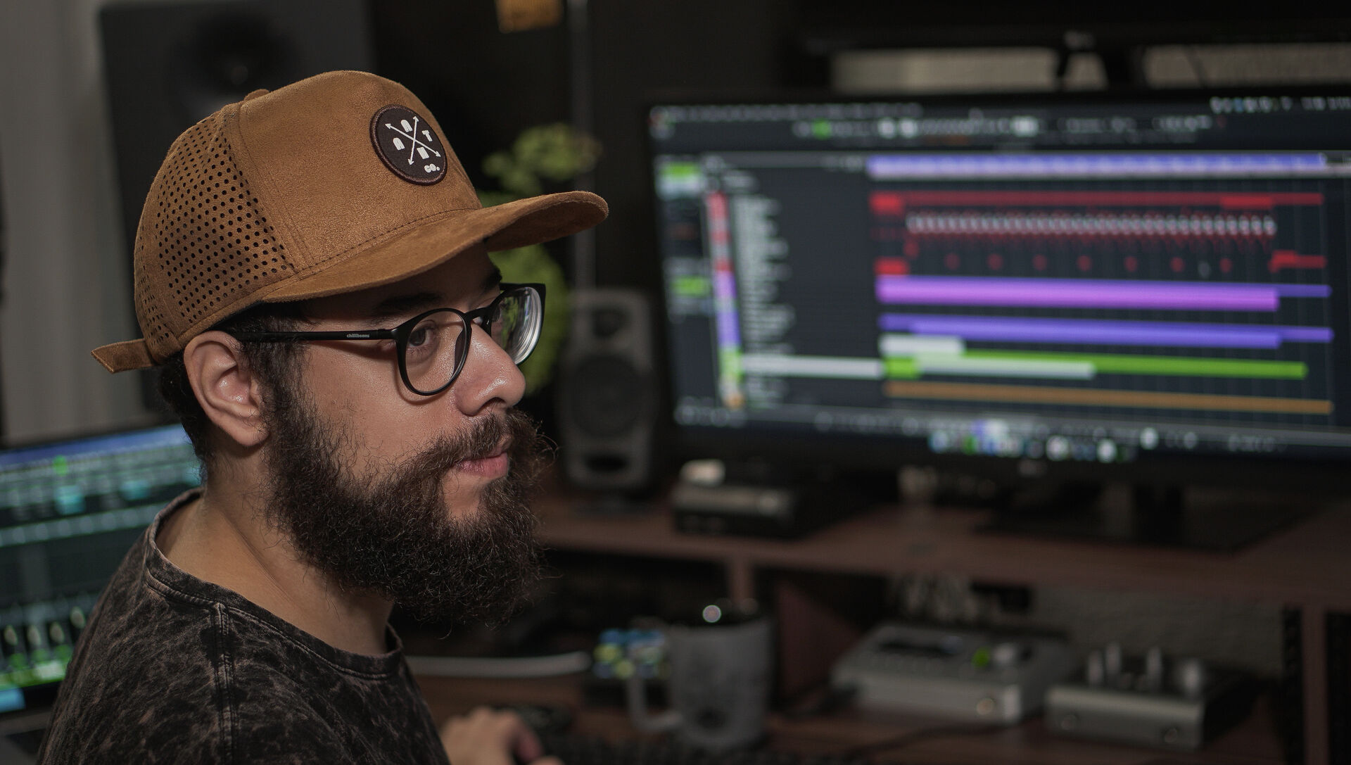 A side on photo of Fernando in a studio. He is wearing glasses and a brown cap.