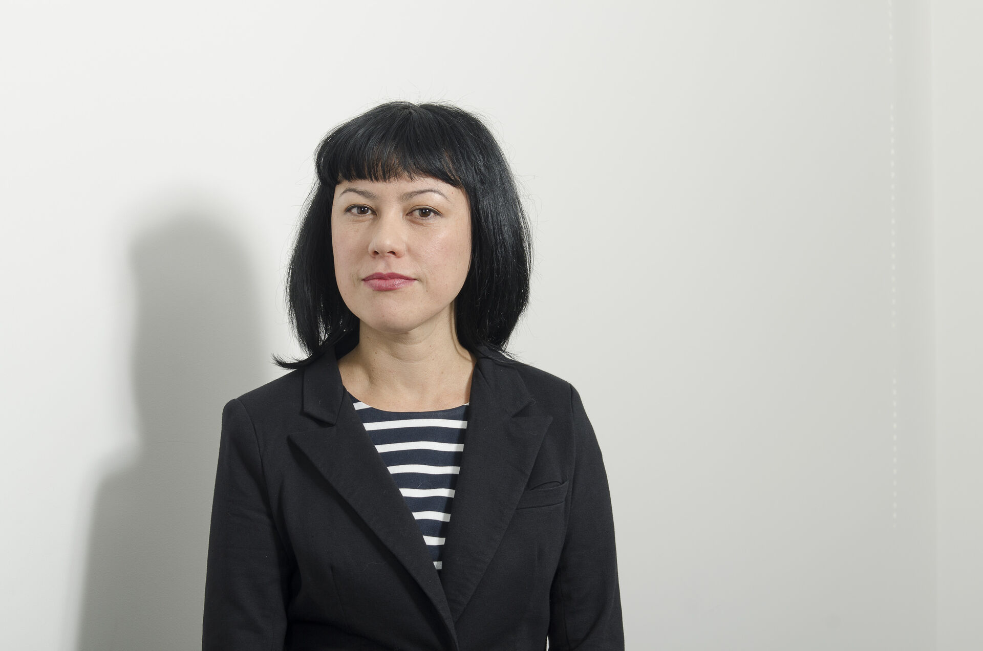 Head shot of Marie Foyle. She is looking at the camera, has long dark hair and is wearing a black & white striped shirt under a black blazer.