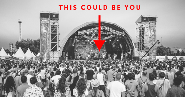 A band plays on a festival stage to a large crowd