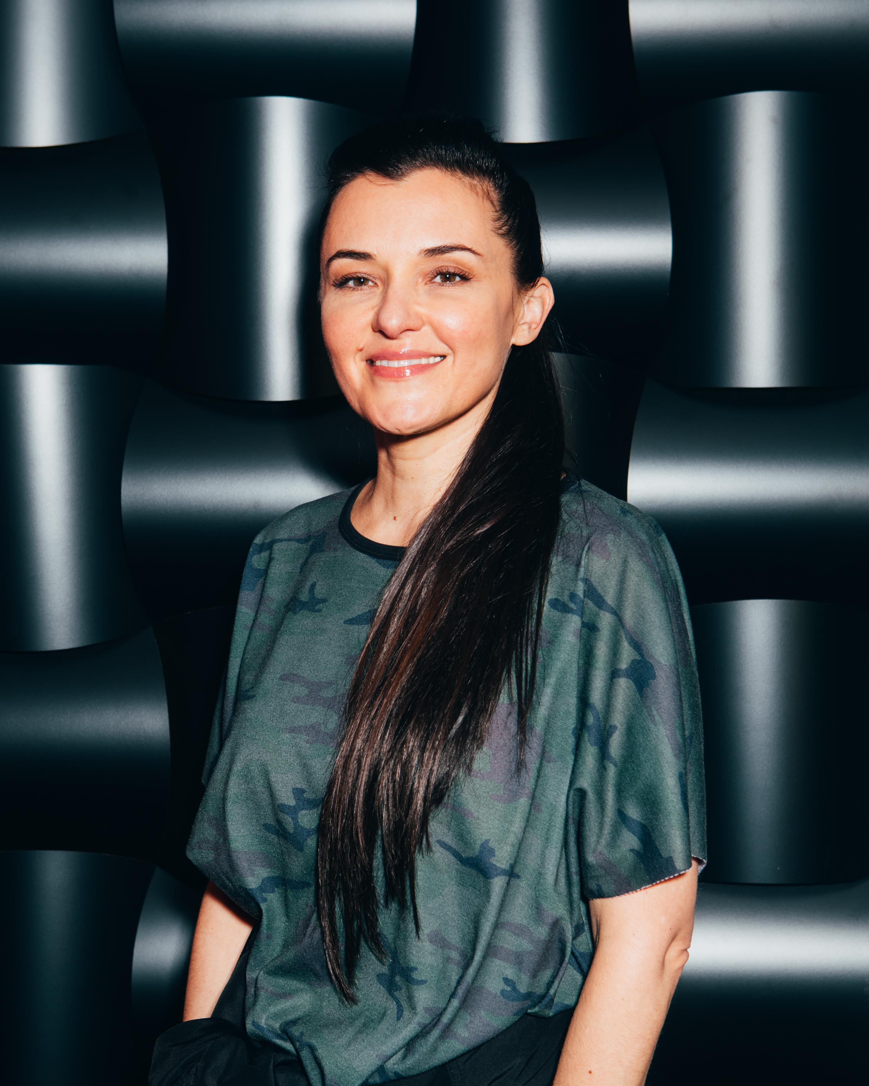 A photo of Amba Sheppard against a black wall