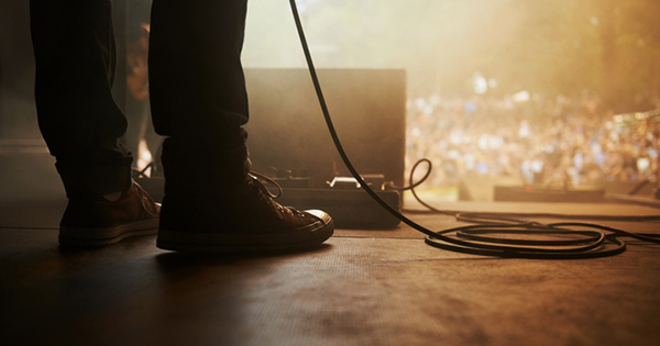 A pair of feet stand on a stage in front of a waiting audience
