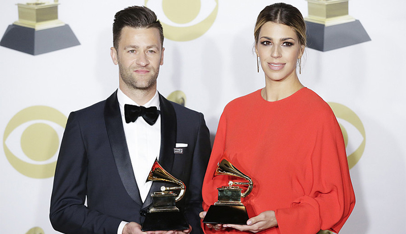 Ben Fielding wearing a tuxedo and Brooke Ligertwood in a red dress stand together holding their grammy trophies