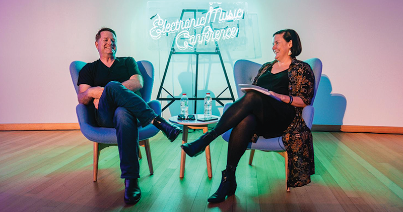 John Watson and an interviewer sitting in armchairs across from each other