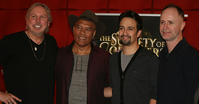 Mark Mancina, Opetaia Foa’i, Lin-Manuel Miranda and Tom MacDougall standing next to each other in front of a red wall
