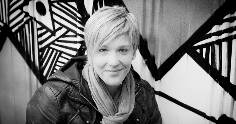 A Black and white Photo of Pru Montin in front of a graffiti’d wall