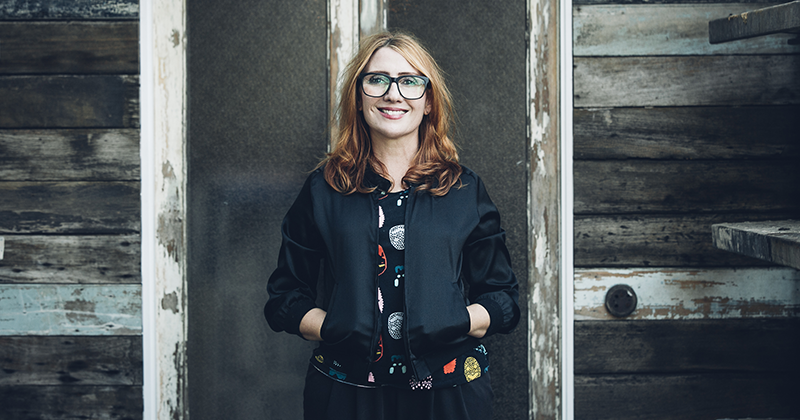 Viv Fantin stands in front of a wall with her hands in jacket pockets